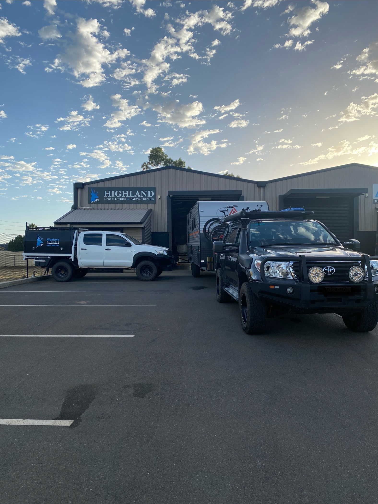 The Highland workshop at dusk, the signwritten ute parked out front and a caravan pulled into the open bay